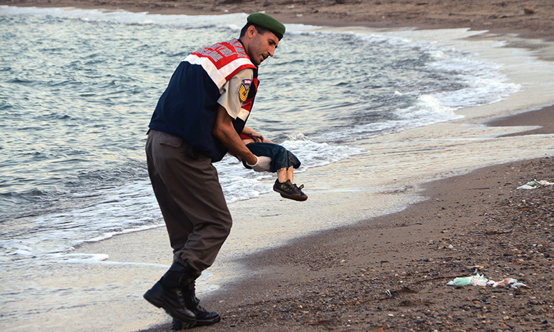 A paramilitary police officer carries the lifeless body of a migrant child after a number of migrants died and a smaller number were reported missing after boats carrying them to the Greek island of Kos capsized, near the Turkish resort of Bodrum early Wednesday, Sept. 2, 2015. (AP Photo/DHA) TURKEY OUT
